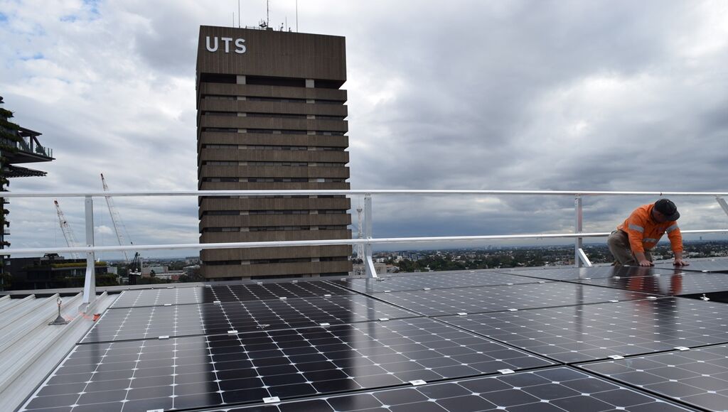 This image shows solar panels from UTS student housing building in the foreground with a university building in the background.